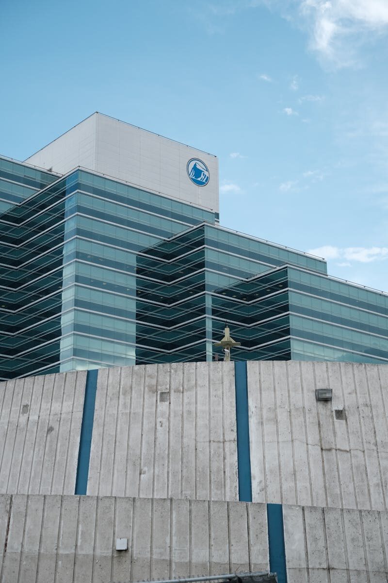 Striking modern glass building featuring unique wave-like architecture against a clear blue sky.