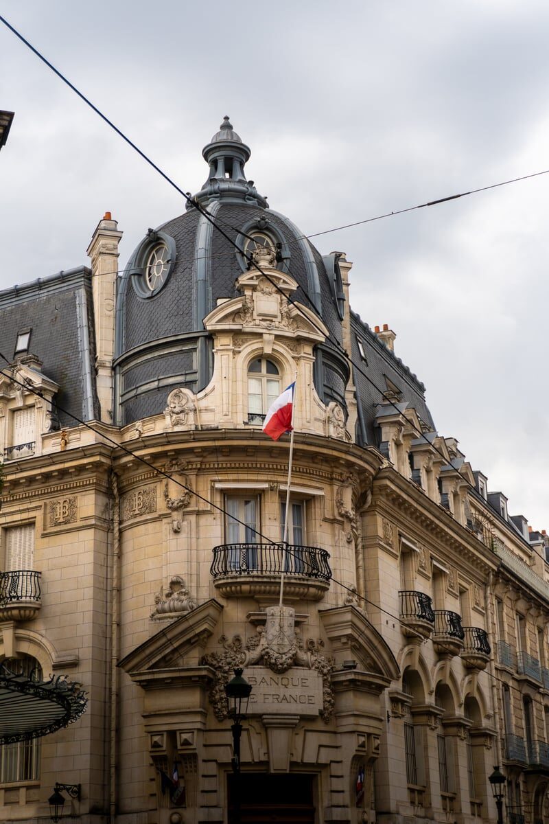 Elegant architectural detail of Banque de France building in Orléans with French flag.