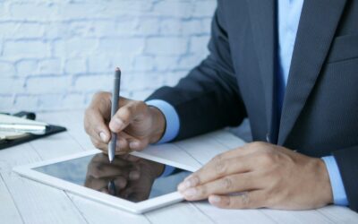 a man in a suit writing on a tablet