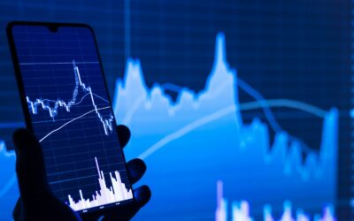 a person holding a cell phone in front of a stock chart