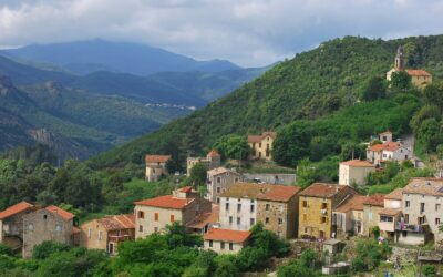 a small village on a mountain side with mountains in the background
