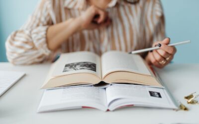 A person engaged in studying with books and a pen, focused and learning.
