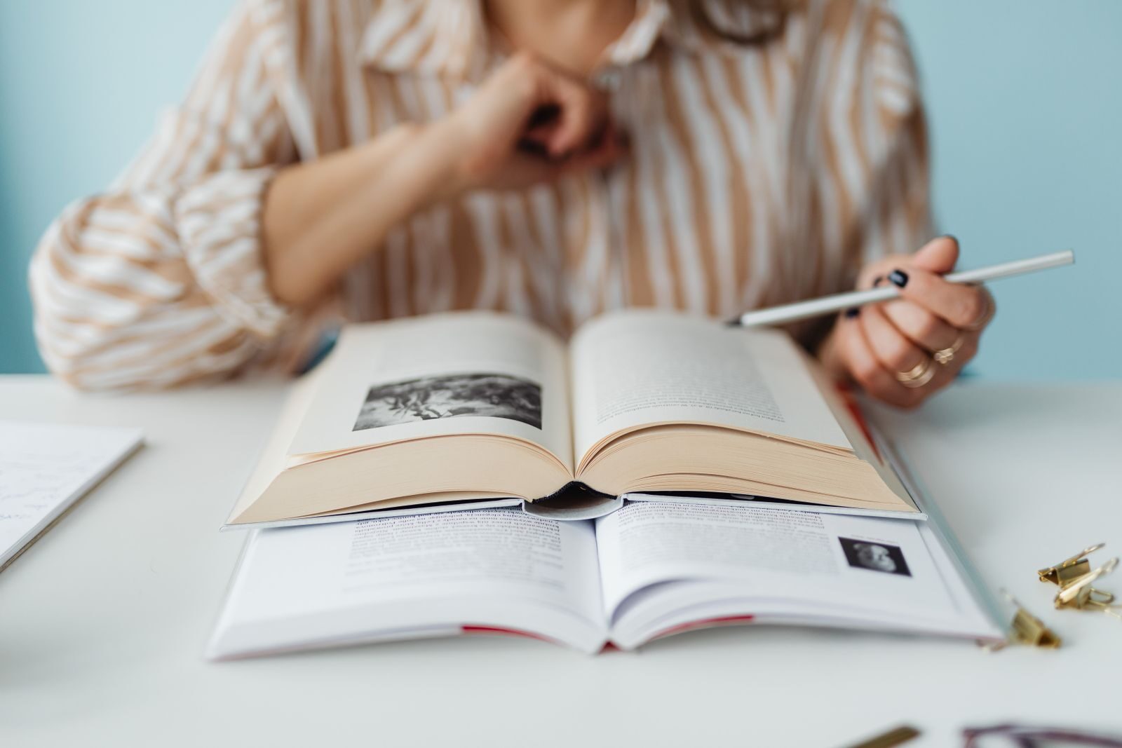A person engaged in studying with books and a pen, focused and learning.