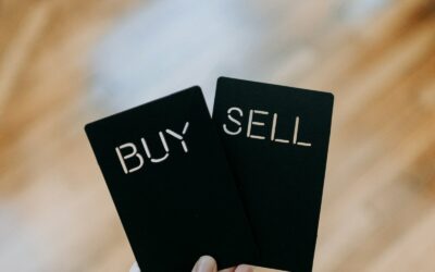 a hand holding two black cards with the words buy and sell written on them