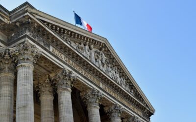 a tall building with columns and a flag on top of it