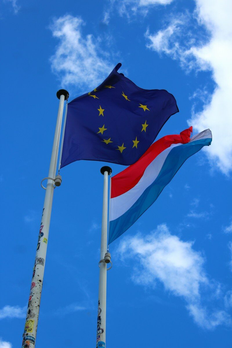 Flags of the eu and luxembourg wave in the sky