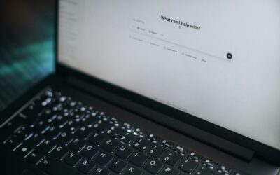 A laptop displays "what can i help with?"