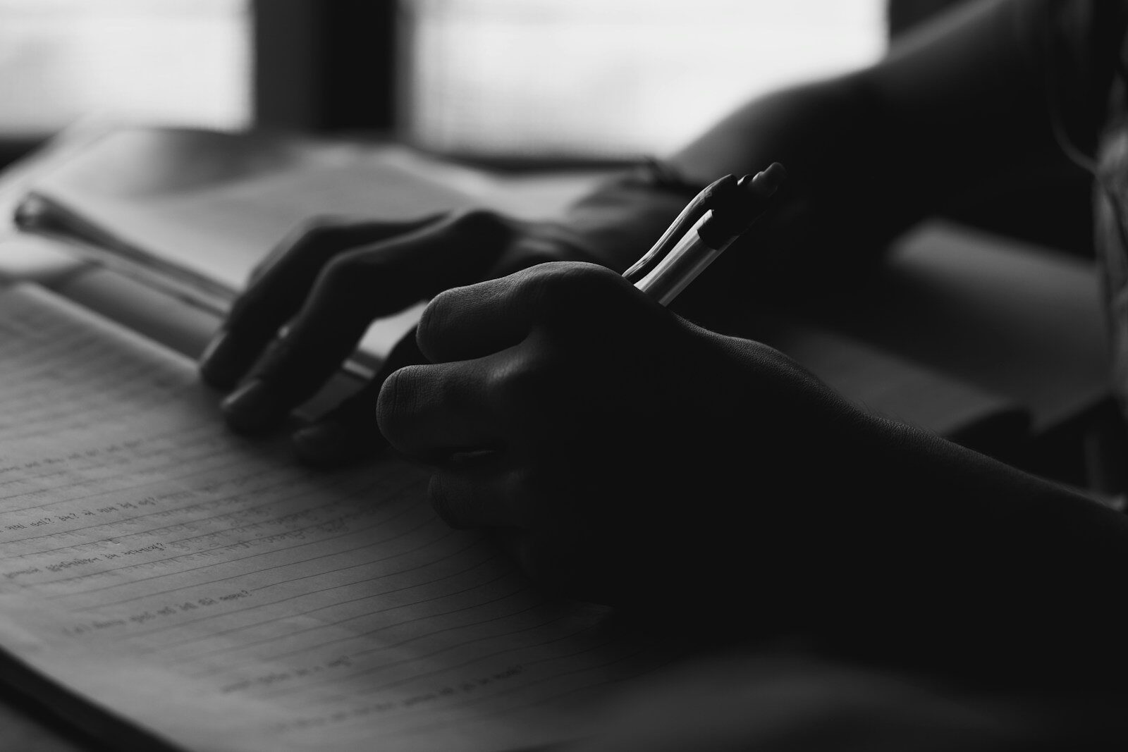a person writing on a notebook with a pen