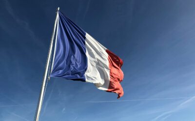 The French flag waving on a flagpole against a clear blue sky