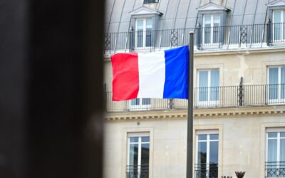 A flag flying in front of a tall building