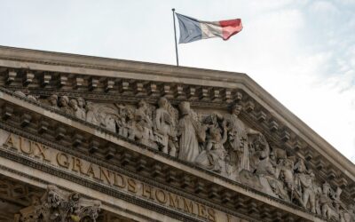 A french flag flies over a detailed building
