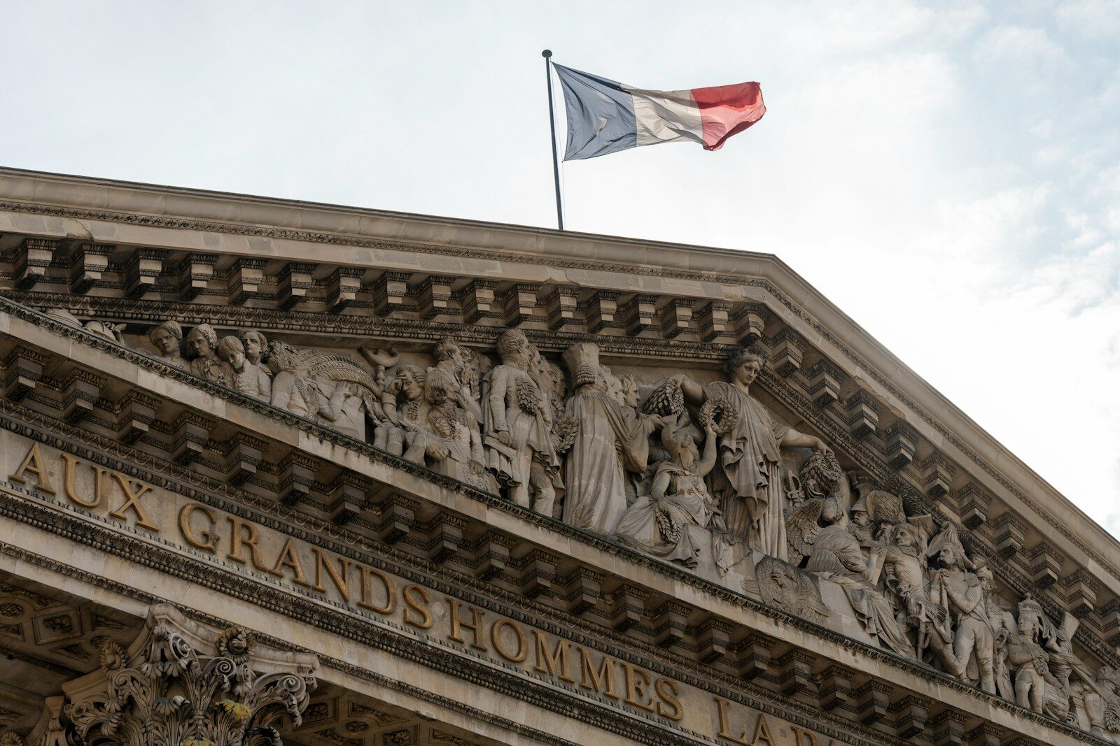 A french flag flies over a detailed building
