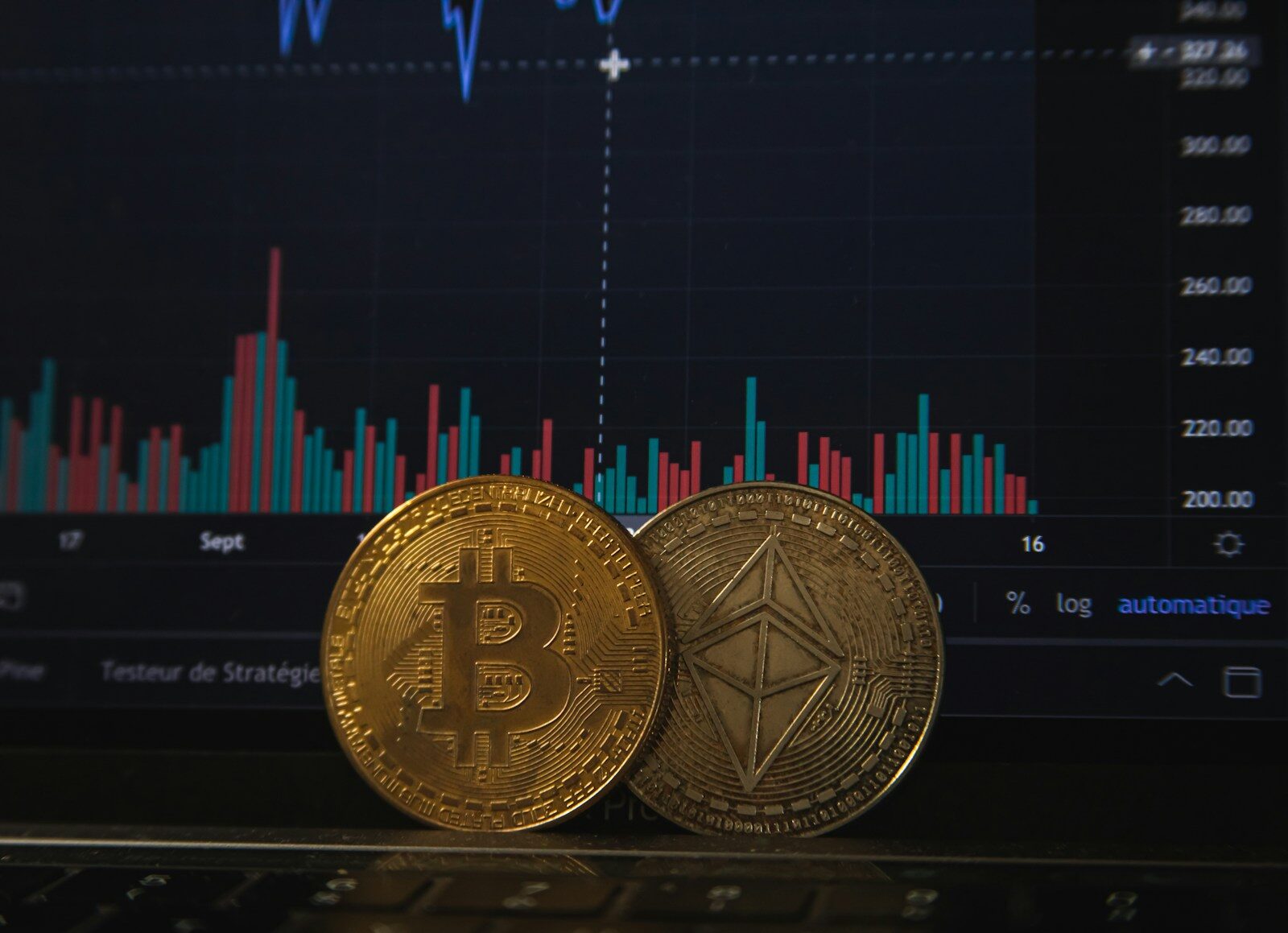 Écran de cotations affichant le graphique du cycle du bitcoin, avec une pièce physique au premier plan